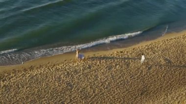 Genç çift - uzun ışık elbise ve yakışıklı bir adam güzel kız şakacı kumsalda coastine çalışır