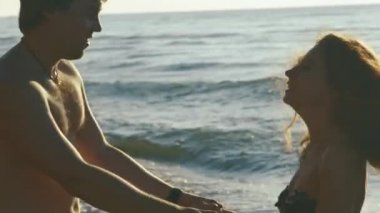 Mutlu genç çift sörf dalgalar kum plajındaki oynamak. Yakışıklı adam tutuşup güzel kızla swirls.