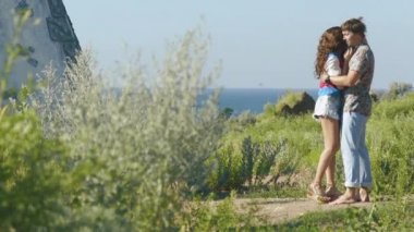 Güneşli havalarda romantik deniz fenerinde kucaklayan, genç bir çift. Arkadan Görünüm