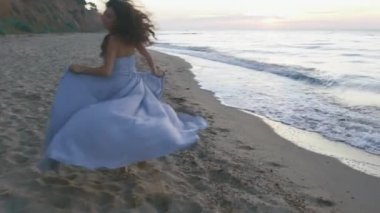 Uzun ışık elbise genç güzel kız şakacı kumlu plaj ve etrafa coastine çalışır