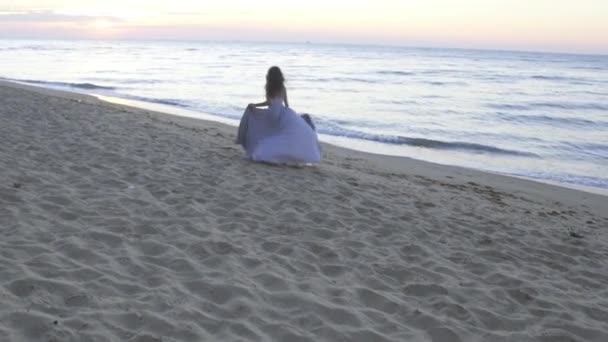 Giovane romantica coppia amata - bella ragazza in abito lungo leggero e bello uomo corre giocosamente lungo la costa sulla spiaggia di sabbia — Video Stock