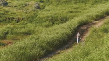 Güneşli gün kıyı şeridi lighthouse yakınındaki kum izinde yürüyen genç barefeet adam