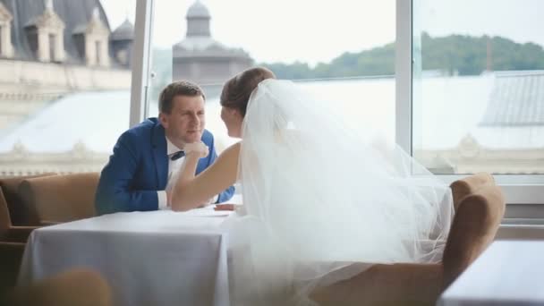 Moment van liefde. Gelukkig jonggehuwden zittend en liefdevol kijken naar elke othet in een café met panoramisch uitzicht op de stad — Stockvideo