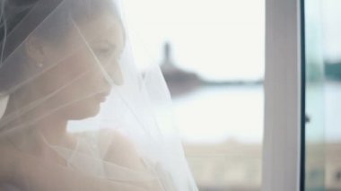 Lüks kafede pencerede inanılmaz şehir manzarası izlerken şeffaf peçe kaplı muhteşem düşünceli sarışın gelinin yakın çekim yüzü