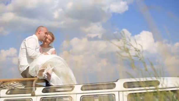 Чарівна молода весільна пара цілується на даху автобуса в полі — стокове відео