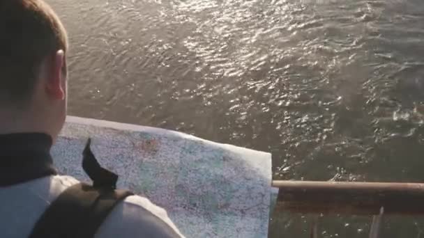 Nahaufnahme von einem Touristen, der auf der Brücke steht und die Landkarte liest, um Gebiete ins Visier zu nehmen. ruhiges Flusswasser Hintergrund — Stockvideo