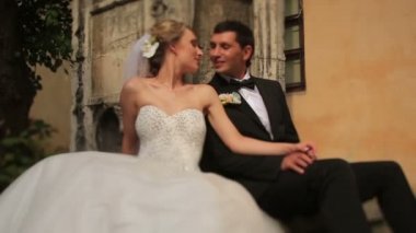 Muhteşem sarışın yeni evli gelin ve yakışıklı damat Lviv eski barok binanın önünde öpüşme. Güneşli düğün günü, ihale anı