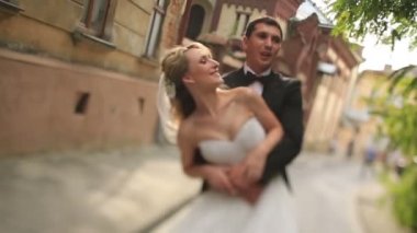 Mutlu damat Lviv eski bir Hıristiyan kilisesi önünde onun güzel sarışın gelin iplik.