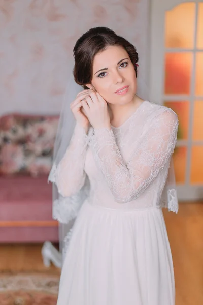 Portrait de charmante mariée en robe de mariée. Belles jeunes femmes habillant ses boucles d'oreilles se préparant pour la cérémonie — Photo