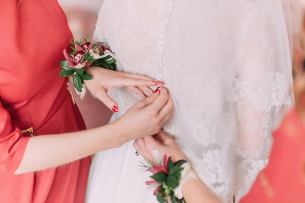 Подружка невесты помогает починить пуговицы на спине невесты — стоковое фото