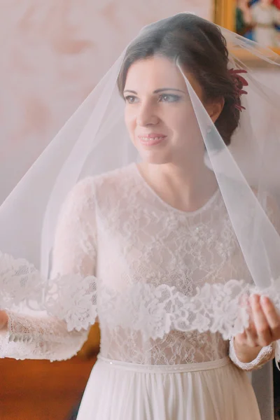 Primer plano retrato de la novia hermosa en vestido de novia con velo largo posando en el interior en el vestidor —  Fotos de Stock