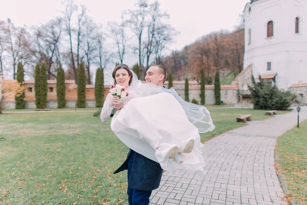 Casal recém-casado apaixonado feliz andando em belo parque verde. Amoroso noivo segurar sua nova esposa em mãos — Fotografia de Stock