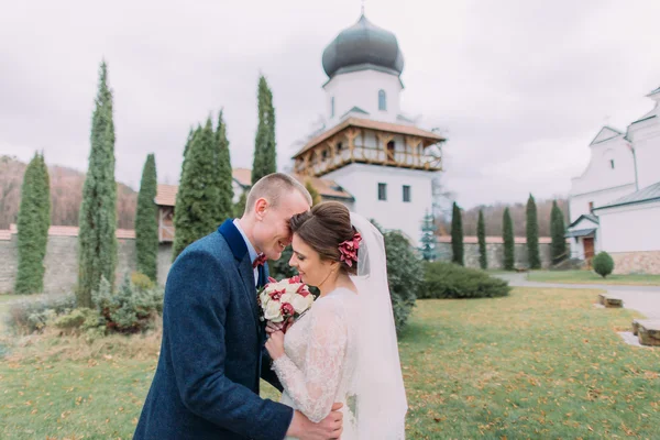 Recém-casados apaixonados têm momento íntimo doce no parque verde romântico perto do mosteiro antigo — Fotografia de Stock