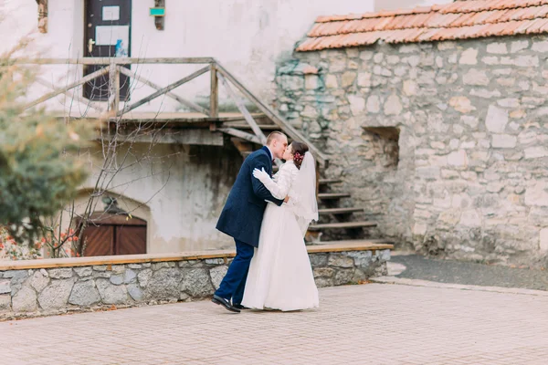 Romantica e appassionata coppia di sposi che si baciano sullo sfondo delle antiche fortificazioni del castello — Foto Stock