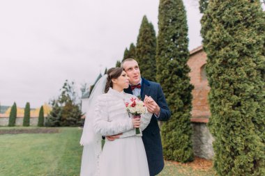 Yakışıklı damat şefkatle onun zarif yeni eşi elini tutarak her ikisi de yeşil parkta selvi satır yakınında evlilik hayatı hakkında hayal