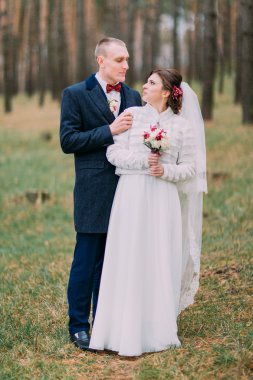 Mutlu şık yeni evli çifti genç çam ormanında poz. Tam uzunlukta