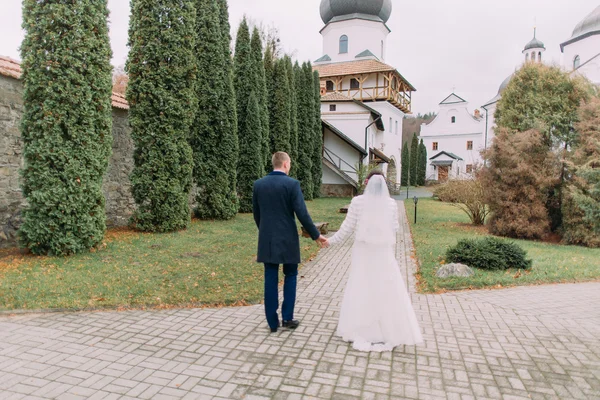 Schöner Bräutigam spaziert mit seiner Frau im romantischen Park des antiken Klosters — Stockfoto