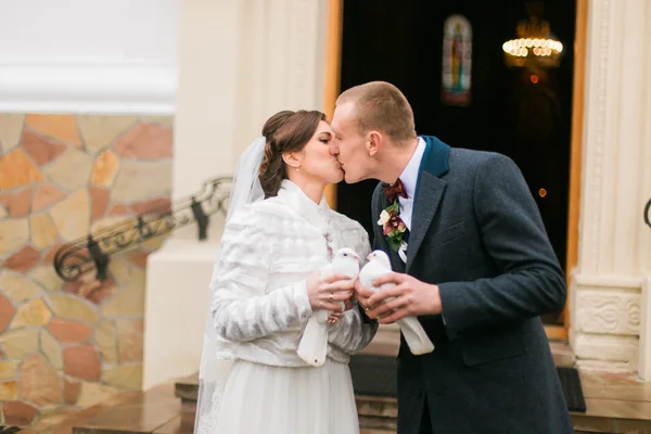 Casal recém-casado liberando pombas ao deixar a igreja após a cerimônia de casamento — Fotografia de Stock