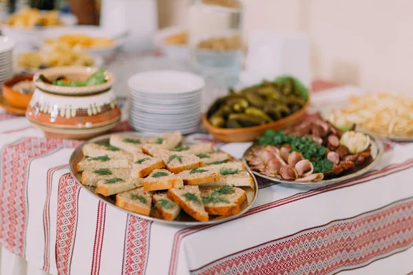 Close-up van vis broodjes, verschillende zoute snacks en augurken in etnische aardewerk op horeca tafel banketzaal — Stockfoto