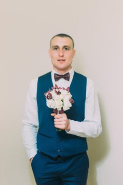 Boş beyaz arka planda poz gül zarif buket tutan şık giyinmiş adam