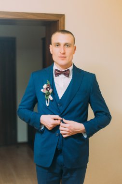 Onun Blazer kapalı sabitleme düğmeleri poz mavi elbise giymiş yakışıklı genç kısa saçlı atletik adam