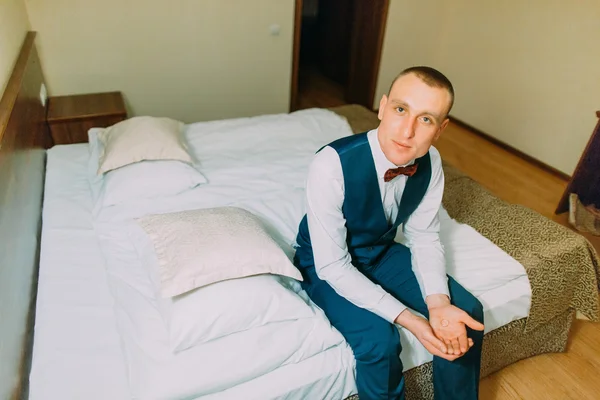 Jovem atlético sentado em um quarto de hotel na cama e olhando para a câmera — Fotografia de Stock
