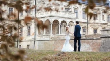 Güzel genç gelin ve damat ortaçağ kale topraklarında açık havada yürüyüş. Yaratıcı düğün kutlaması