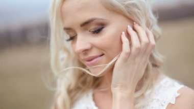 Yakın büyülü güzel genç sarışın gelin yavaşça yüzüne dokunmadan. Açık bulanık arka plan