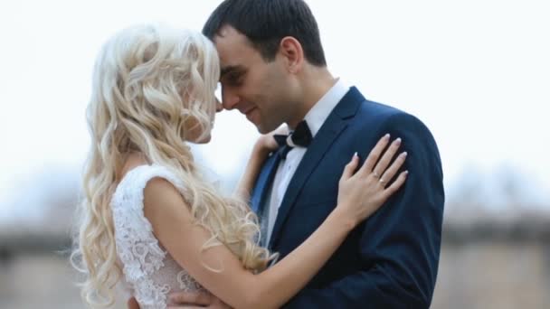 Hermosos recién casados amorosamente se miran el uno al otro en un fondo borroso — Vídeo de stock