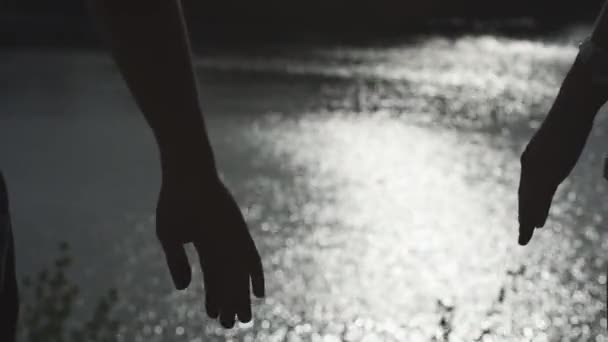 Le sagome di mani di coppia felici che tengono insieme di sera con superficie dell'acqua del fiume su sfondo — Video Stock