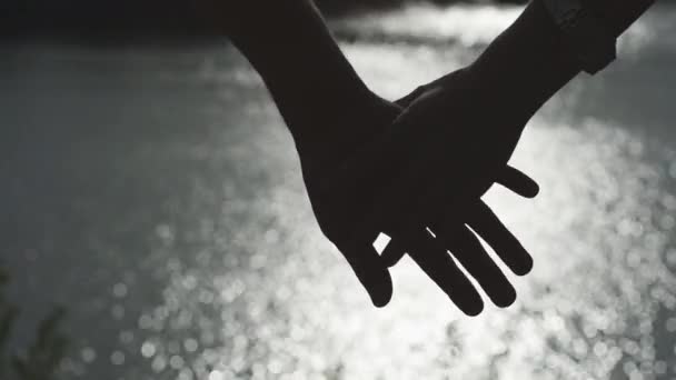 배경에 강 물 표면과 함께 들고 행복 한 커플 손의 실루엣. 공생 개념 — 비디오