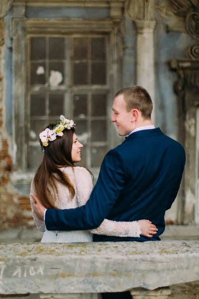 Esposo sensual e esposa abraçando sob arco no palácio arruinado antigo. Visão traseira — Fotografia de Stock