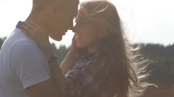 Cerca de pareja adolescente en el amor besar al aire libre en el día soleado brillante. Brisa ligera agitando el pelo de las niñas. Tono de filtro cálido — Vídeo de stock