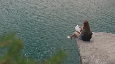 Genç aktif backpacker kız dağ kayanın üzerine büyük su yüzey dağ Gölü'nün ve seyir üzerinde dinlenme eşlemek için
