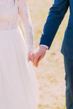 Evli gelin ve damadın el ele tutuşuyakından görünümü