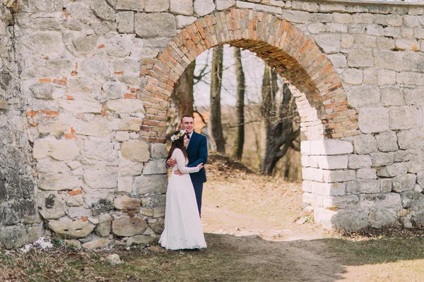 Brautpaar posiert am alten zerstörten Tor der alten barocken Burgmauer — Stockfoto