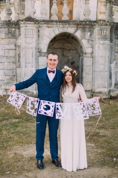 Счастливые жених и невеста держат художественные буквы любви — стоковое фото