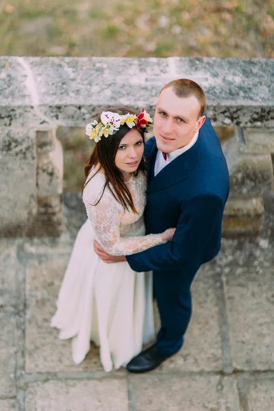 Feliz noivo abraçando com sua noiva bonita, enquanto ambos estão em escadas de pedra antiga. Vista de ângulo alto — Fotografia de Stock