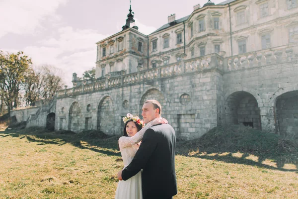 Affascinanti sposi che camminano vicino a un bellissimo palazzo barocco in rovina — Foto Stock