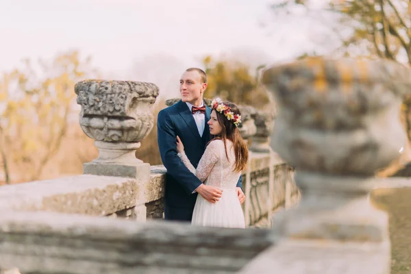 Πορτραίτο του χαρούμενος νεόνυμφο κομψό νύφη και ο γαμπρός θέτοντας σε παλιά πέτρινη βεράντα στο πάρκο άνοιξη γάμος — Φωτογραφία Αρχείου
