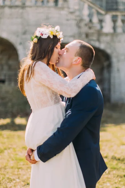 Couple nouvellement marié pose près de vieux mur voûté en ruine. marié athlétique tient sa jolie mariée sur les mains — Photo