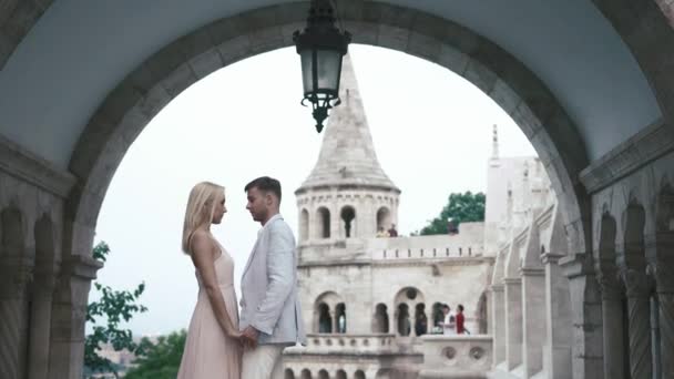 Casal de luxo abraçando e beijando no fundo do castelo antigo magnífico branco — Vídeo de Stock