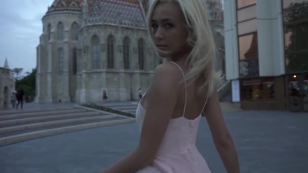 Charmant sexy blondine het dragen van een sexy roze jurk wandelen in Boedapest en genieten van het stadsgezicht Panorama in Twilight — Stockvideo