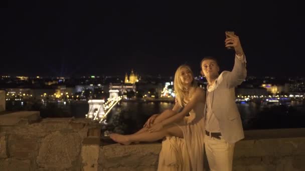 快乐爱对年轻夫妇有一个有趣的浪漫的散步和以自拍照在宏伟布达佩斯模糊背景 — 图库视频影像