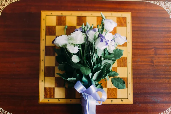 체스판에 백색 장미의 꽃다발입니다. 나무 테이블 배경에서 절연 — 스톡 사진