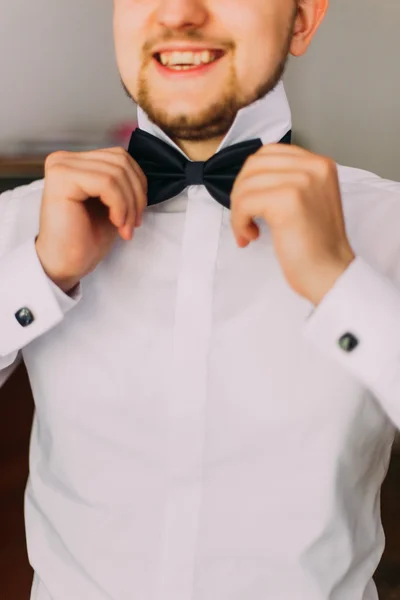 Jeune homme beau avec une barbe courte dressing noeud papillon dans sa main — Photo