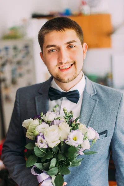 Красивий молодий наречений тримає весільний букет з білих троянд — стокове фото