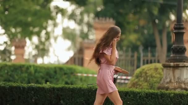 Joven estudiante bastante femenino sosteniendo libro mientras corre en el carril del parque y accidentalmente golpea con el joven dejando caer el libro de la escuela — Vídeo de stock