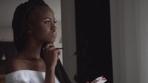 Close-up van portret van een charmante Afrikaanse vrouwelijke fashion model iets te typen op de tablet op lege witte achtergrond — Stockvideo