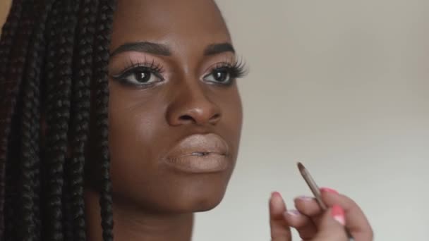 Artista de maquillaje hace un hermoso maquillaje para hermosa chica afroamericana — Vídeo de stock